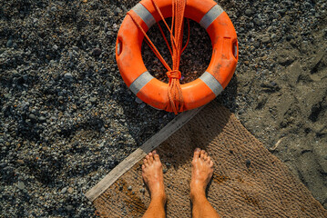 POV of man looking down at his legs andthe life ring on the beach