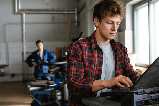 A man uses a laptop working in the garage