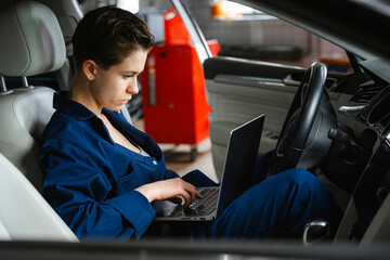 An auto mechanic performs computer diagnostics of a car