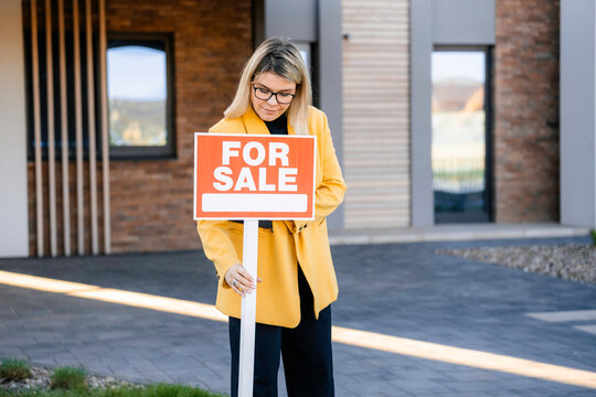 A woman removes the "for sale" sign