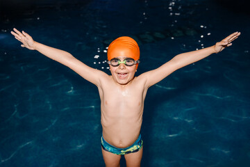 Joyful young boy celebrates in the swimming pool at night