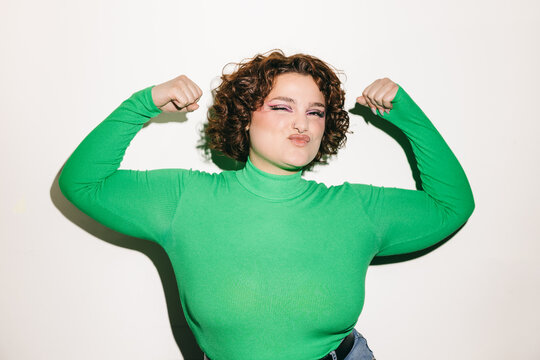 Confident curly-haired woman posing in green top