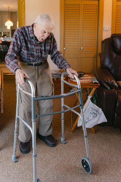 senior citizen walking in his living room with the help of. walker