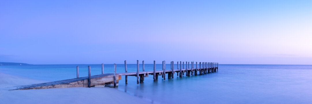 Long wooden pier in calm waters towards horizon