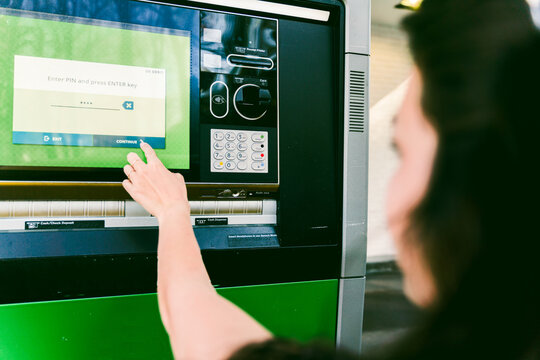 young woman getting cash at drive through ATM