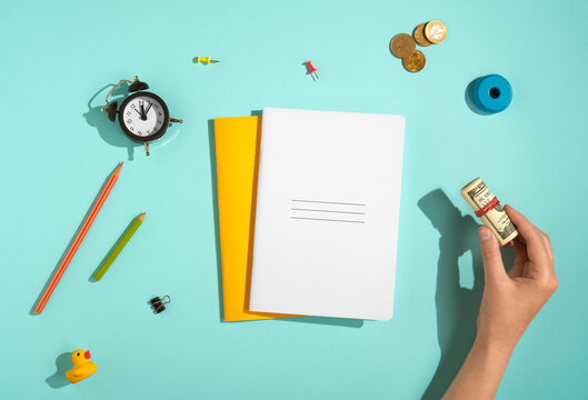 Flat lay of school supplies and hand with cash on blue background. 