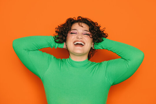 Joyful Young curvy woman laughing with hands behind head