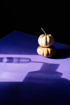 Two pumpkins stack on purple background