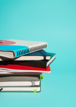 Stack of various notebooks on blue background with copy space.