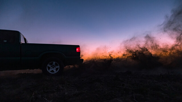 Pickup truck a cloud of dust from  the rear wheels.