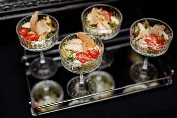 An elegant presentation of gourmet salads served in sophisticated glassware; the colorful medley of fresh vegetables and tender chicken slices.