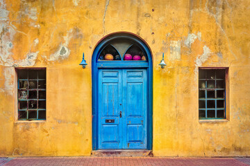 Old yellow paint washed building with blue door