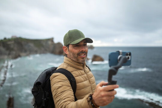 traveler man using mobile phone near the sea