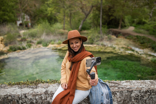 Woman next to a natural water source in nature taking a selfie