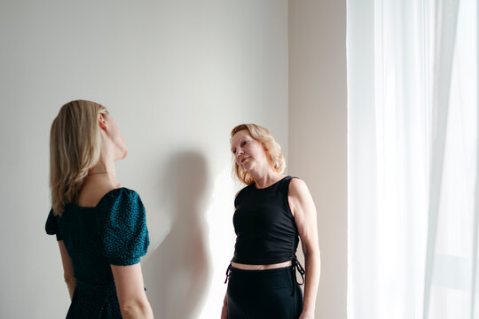 Two women do exercises standing by the window