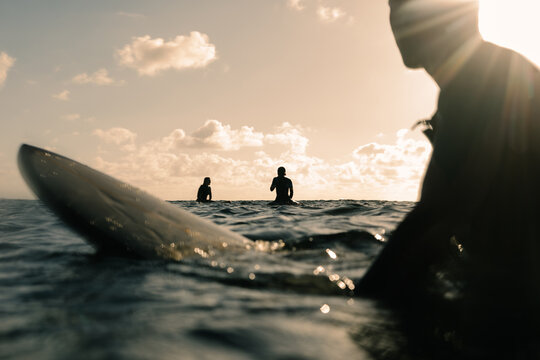 Surfer observes from a distance as two friends enjoy a sunset floating