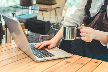 キャンプ場でワーケーション・ノマドワーク・テレワークをする女性キャンパーの手元
