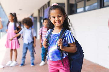 Students, including biracial girl and African American boy, smiling with backpacks