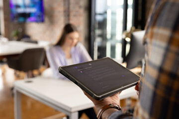 Man using tablet with ai chatbot in office modern workspace with large windows and a blurred backgro