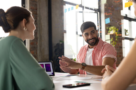 Young Asian man discussing project details with colleagues in modern office