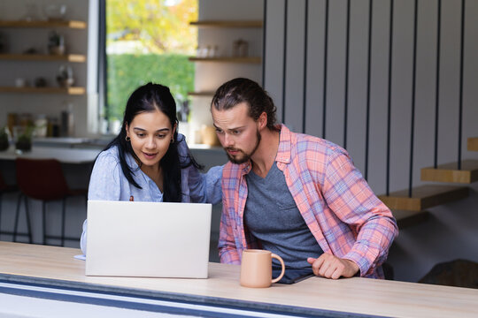 Young diverse couple are looking at a laptop together