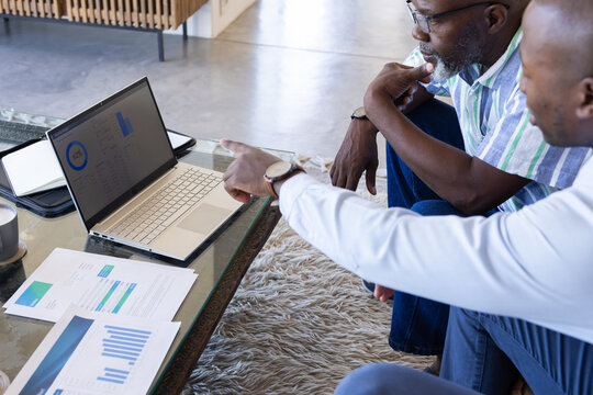 African American father and son are discussing data on laptop screen