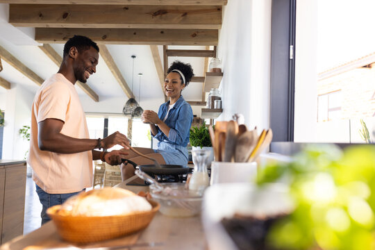 An African American man and biracial woman, diverse couple, are cooking together