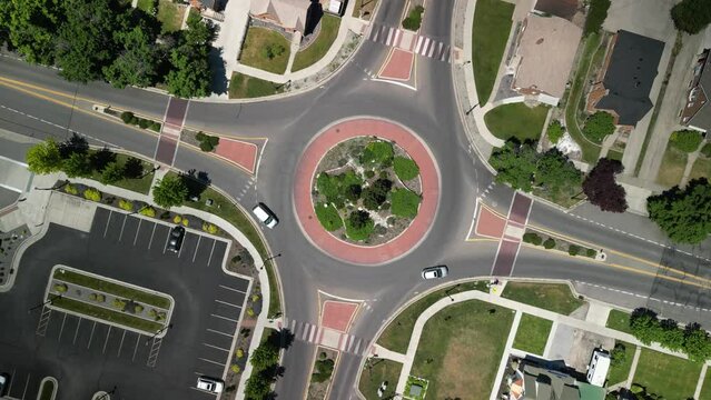Top down descending aerial over roundabout in town of Logan Utah on sunny day