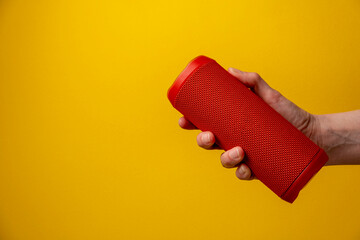 Hand holding bluetooth loudspeaker on yellow background
