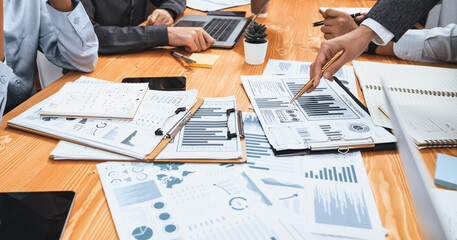 Multiracial analyst team use BI dashboard data to analyze financial report on meeting table. Group of diverse business people utilize data analysis by FIntech for business marketing decision. Concord
