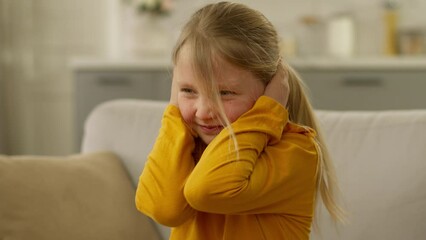 Little European girl cover ears ignoring refusal no shake head sofa naughty child protest daughter offspring disagree denial unhappy negative emotional dissatisfied expression frustrated childish home