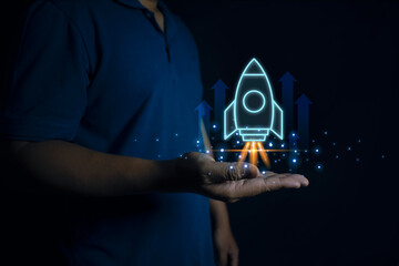 Businessman holding holographic rocket symbolizing startup success and growth acceleration with...