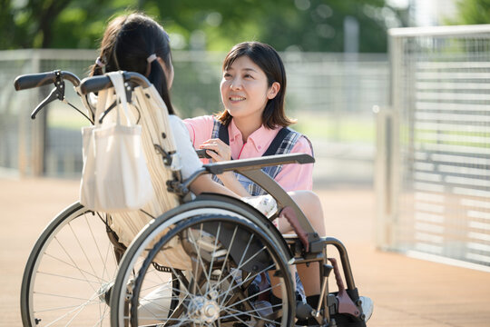 車椅子に乗る子供と介護や補助をする介護士や看護師　上半身　ホームヘルパーやデイサービスのイメージ - Powered by Adobe