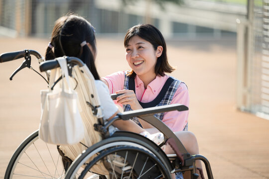 車椅子に乗る子供と介護や補助をする介護士や看護師　上半身　ホームヘルパーやデイサービスのイメージ