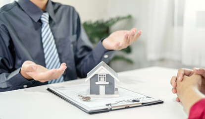 A real estate agent with a House model is talking to clients about buying home insurance. Home insurance concept