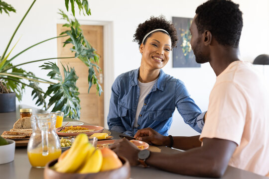 A young biracial woman smiling at her partner while having breakfast together - Powered by Adobe