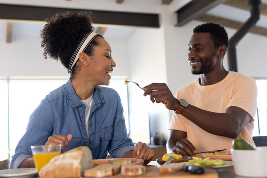 An African American man and a biracial woman, diverse couple, enjoy breakfast together
