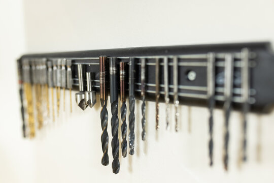 A row of various drill bits neatly organized on wall-mounted rack