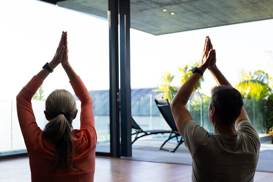 A mature biracial mature couple is practicing yoga together at home, at home