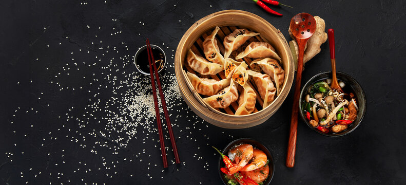 Asian traditional cooked food. Damplings, shrimps and mushrooms soup on black background.Asian traditional cooked food. Damplings, shrimps and mushrooms soup on black background