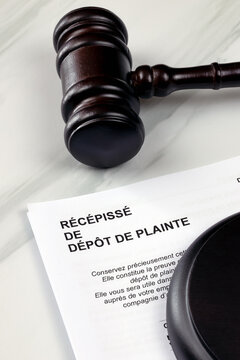Marteau de juge et feuille ou il est &eacute;crit dessus en fran&ccedil;ais "r&eacute;c&eacute;piss&eacute; de d&eacute;p&ocirc;t de plainte". En gros plan.