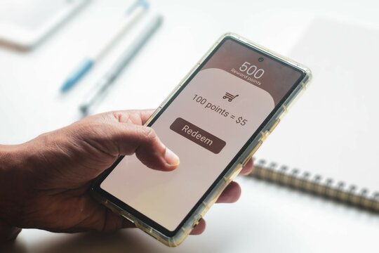 Man trying to convert redeem rewards points into cash on his mobile phone. Loyalty program to increase customer engagement concept in digital marketing. Selective focus.