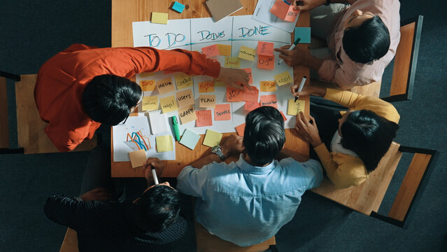 Top view of people writing and making scrum task board while writing marketing and planning strategy at colorful sticky notes. Smart team manage work performance by using kanaban board. Convocation.