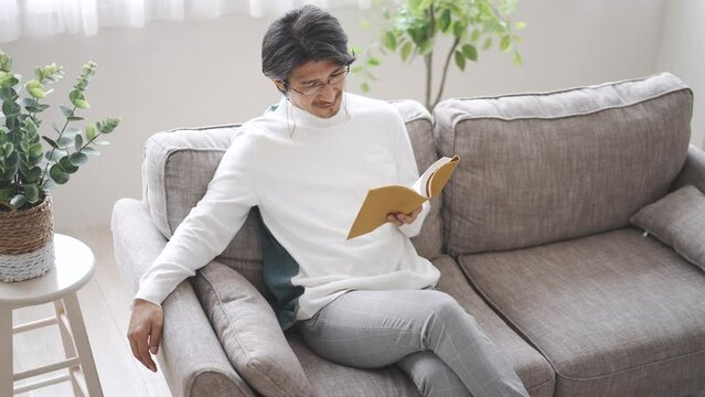 ソファに座って読書する男性