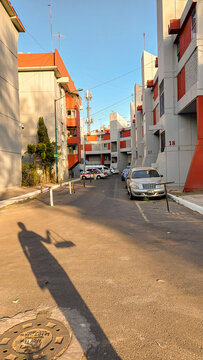 Sombras de personas con una canasta proyectadas en el piso. Atardecer en una calle de la CDMX.