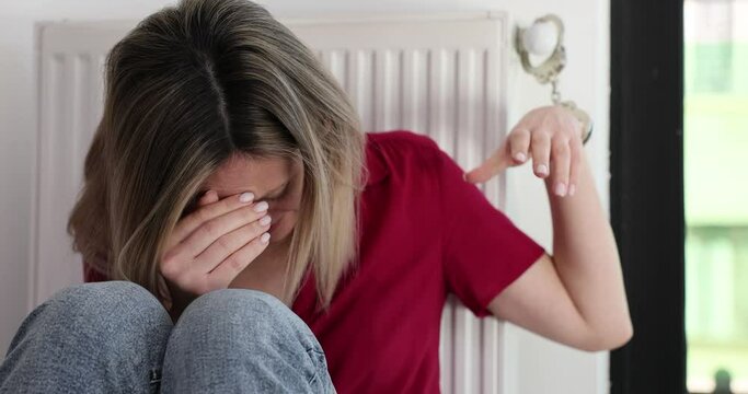 Woman with tears streaming down face handcuffed to radiator
