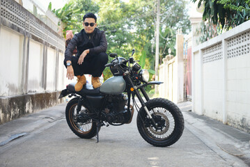 Fototapeta premium Asian man motorbike in black leather jacket travel rider trip. Handsome Men wear sunglass outdoor lifestyle freedom rider. Men trendy hipster cool person. Young asian man hobby ride with motor bike