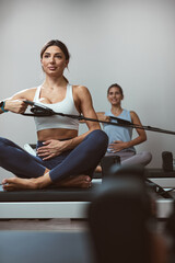 Young women exercising in a gym on pilates machines.