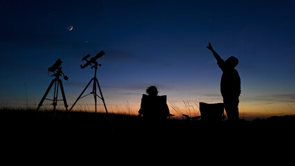 People enjoying watching and stargazing with astronomy telescopes outdoors in nature, observing planets, Moon and other celestial objects. © astrosystem