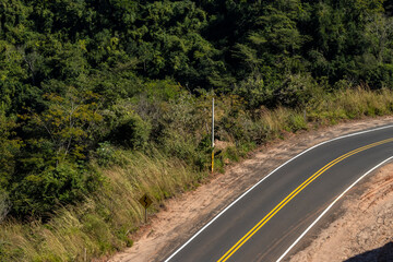 View of an empty paved rural road, flanked by Atlantic forest and eucalyptus fields in a mountain range in Brazil